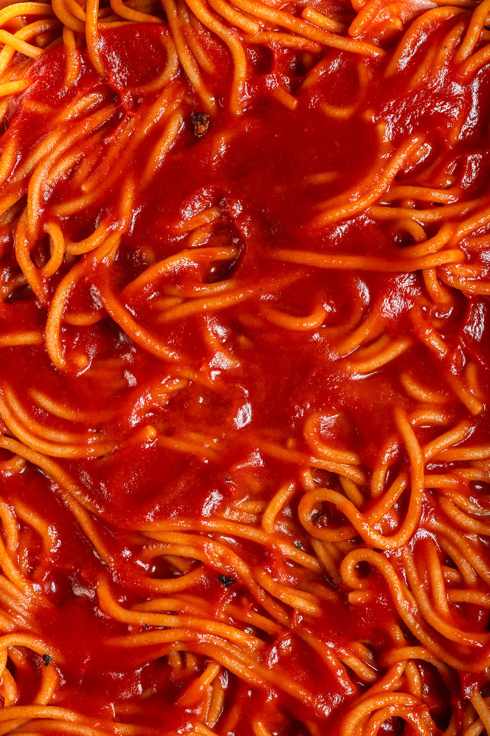 A close-up view of spaghetti noodles generously coated in a vibrant red tomato sauce.