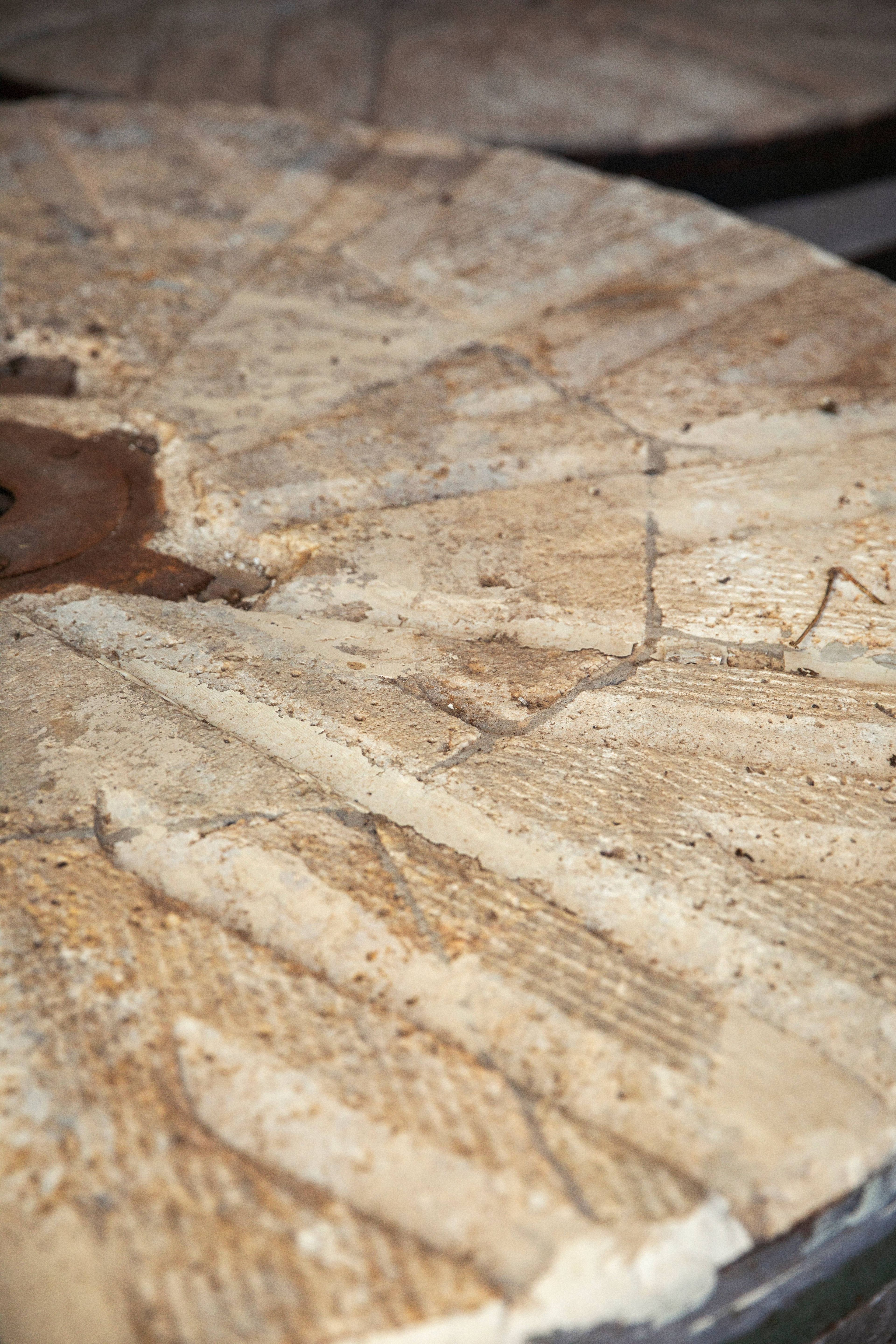 A close-up view of a weathered, textured stone millstone used for grinding grain.
