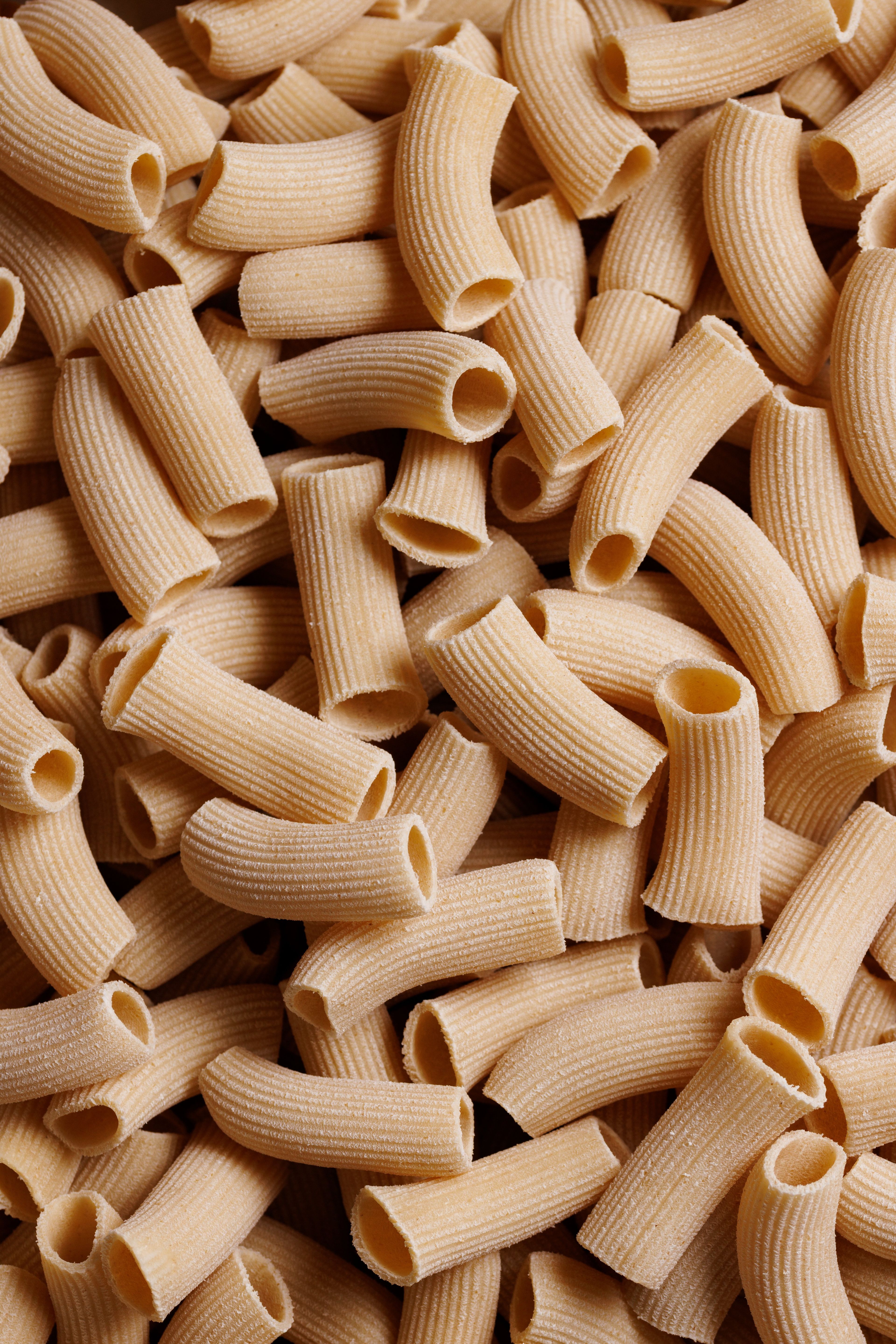A close-up view of a pile of uncooked rigatoni pasta.