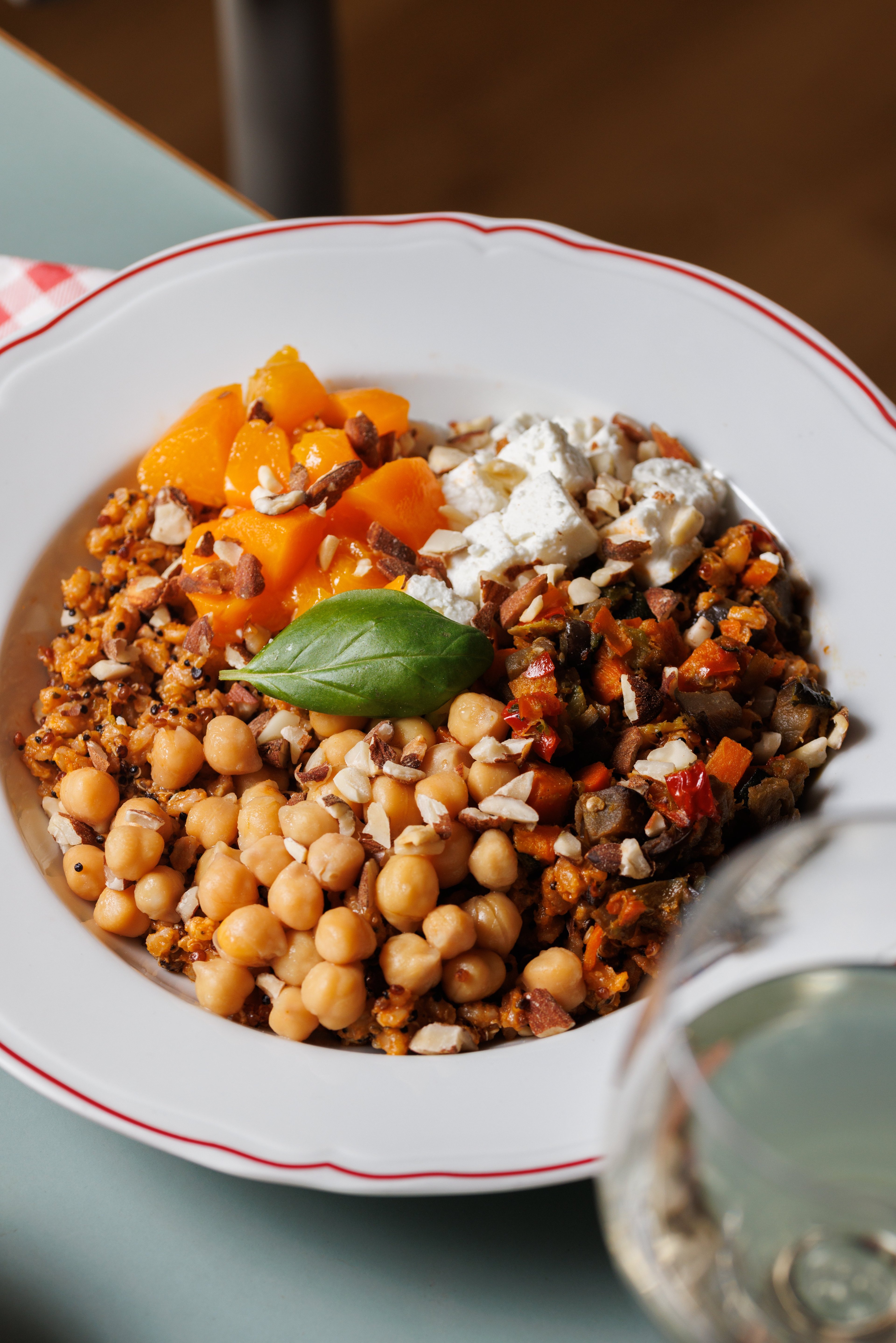 A vibrant, healthy grain bowl topped with chickpeas, roasted vegetables, feta cheese, and fresh basil.