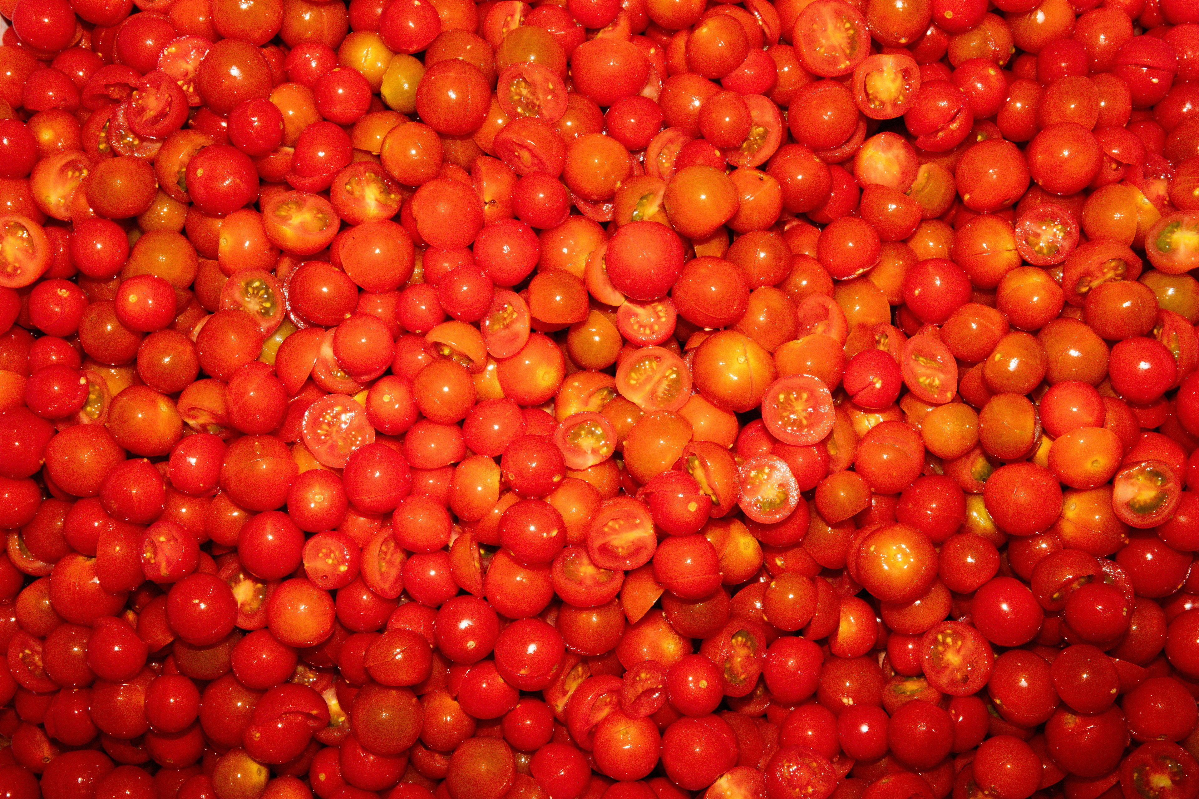 A large pile of fresh, halved cherry tomatoes fills the frame.