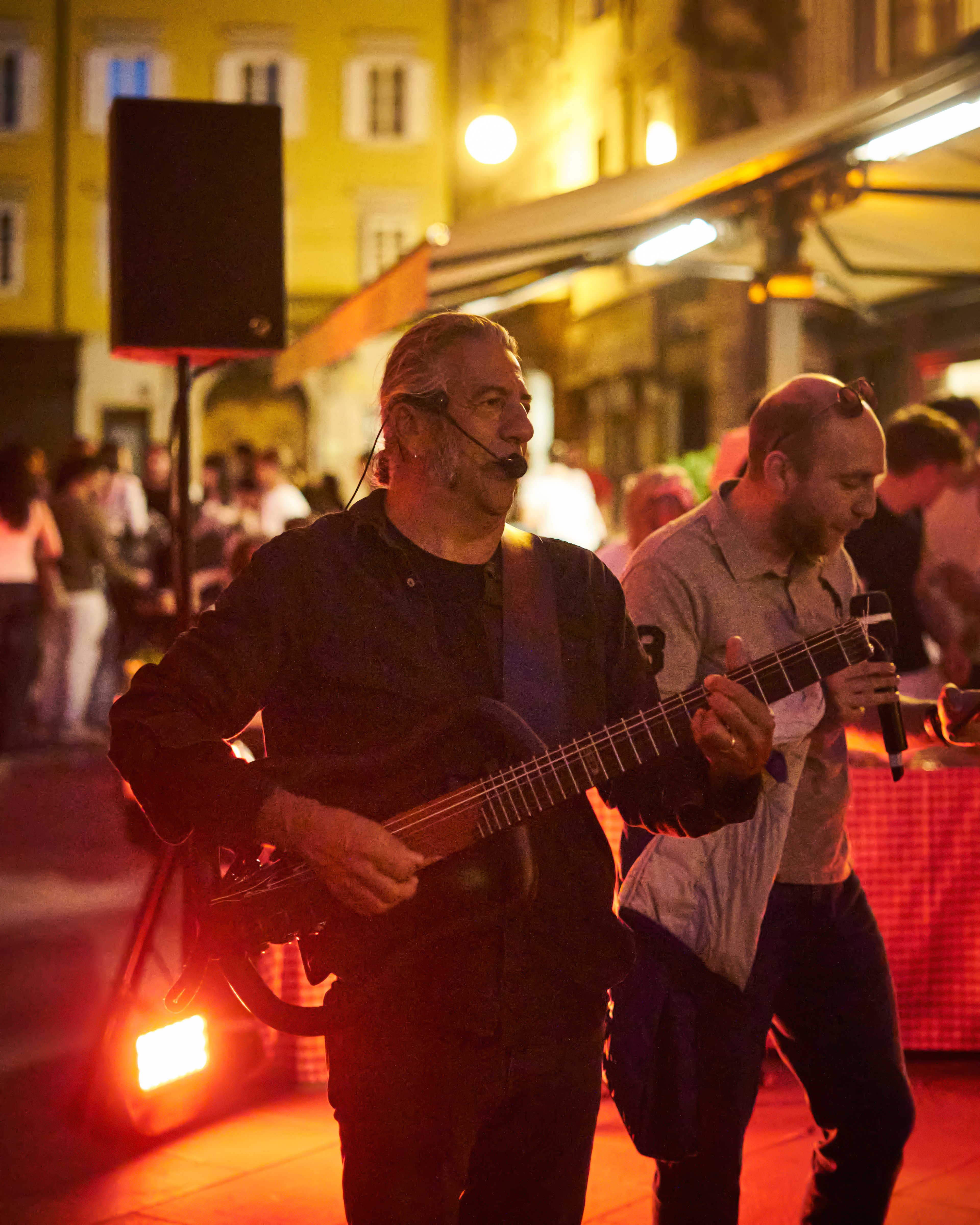 A live musical performance takes place in a vibrant outdoor restaurant setting at night.