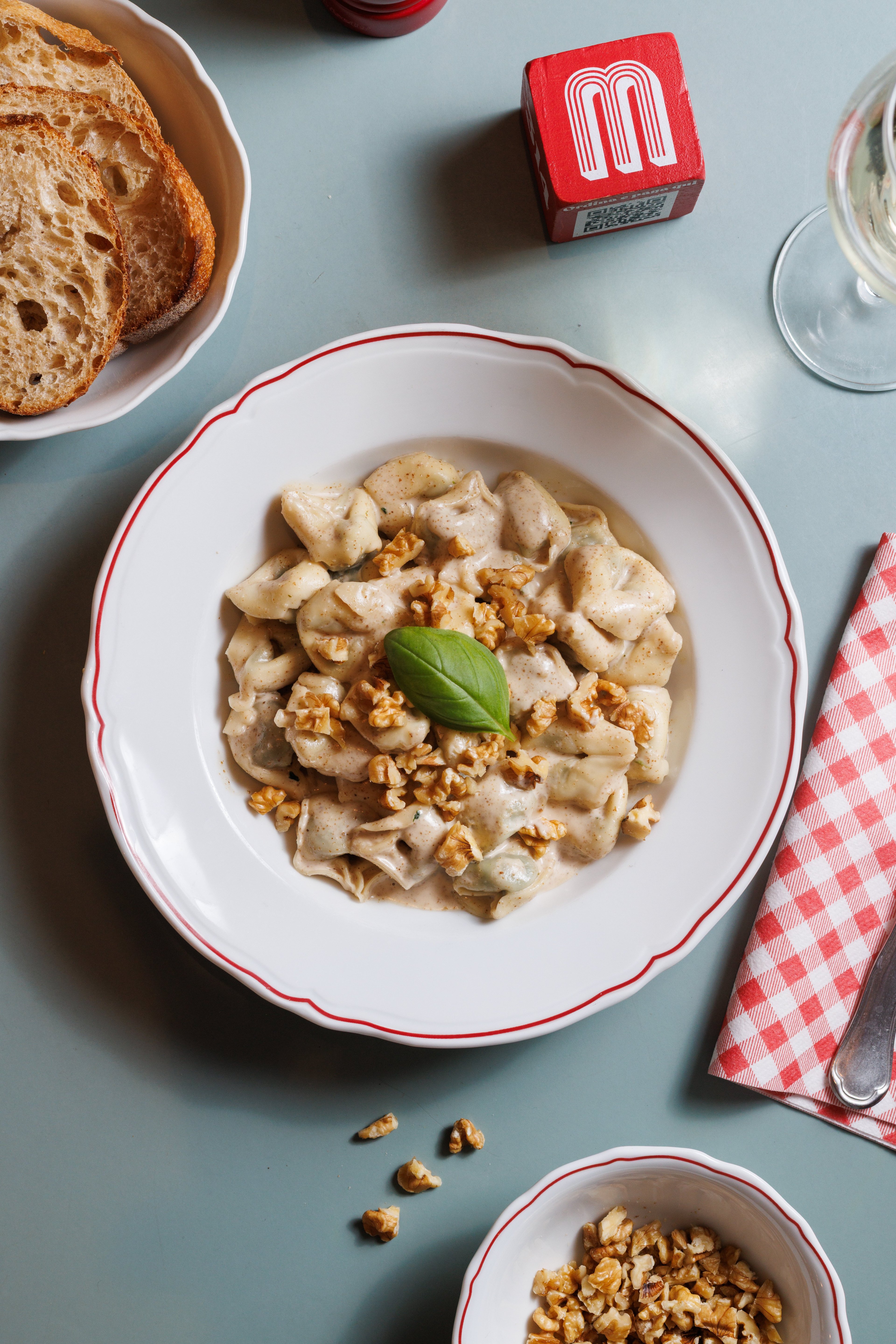 A top-down view of a plate of tortellini in a creamy walnut sauce garnished with fresh basil.